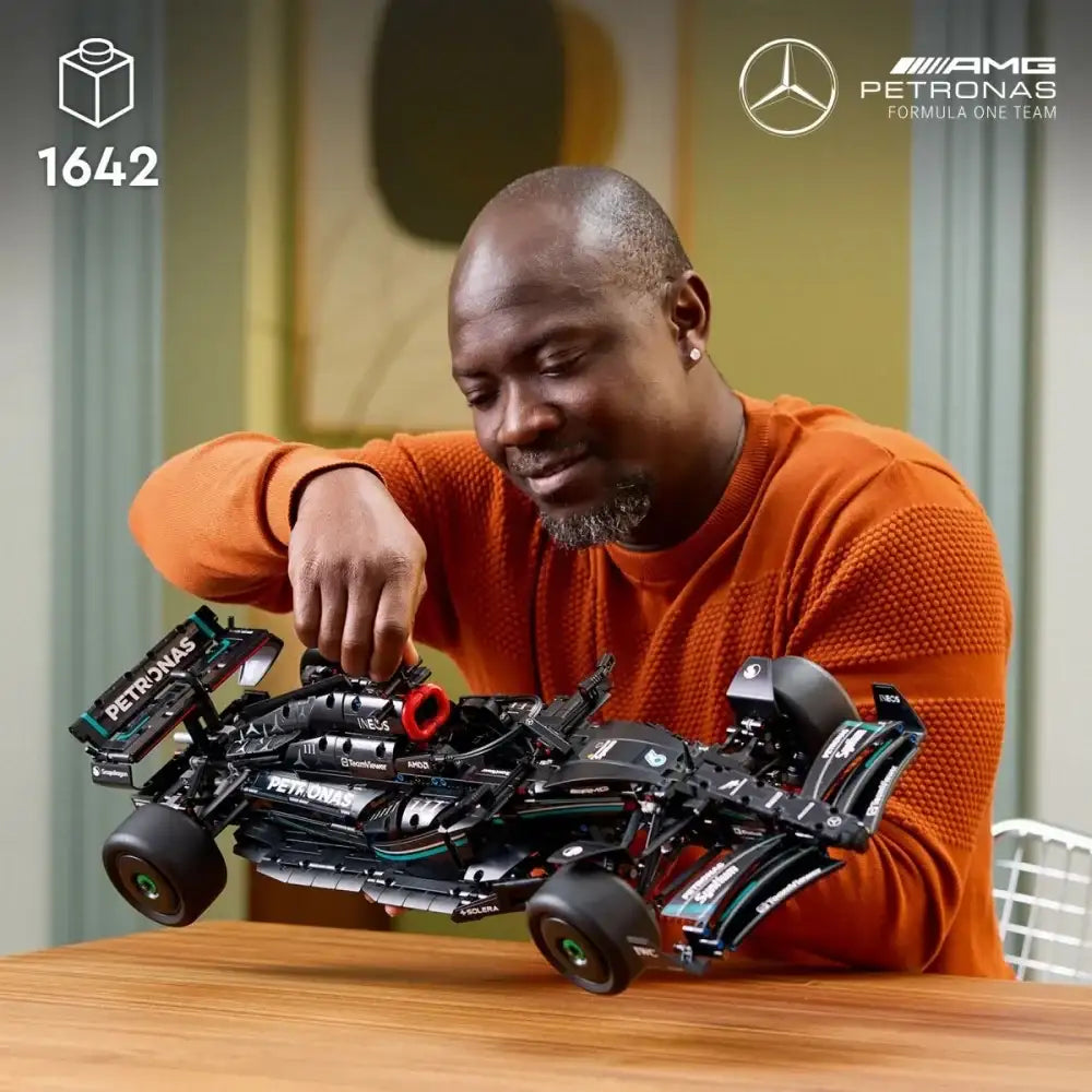 Mężczyzna buduje model wyścigowego samochodu LEGO Mercedes F1 na drewnianym stole, kreatywna zabawka dla dzieci i dorosłych - zabawki-dla-dziewczynki