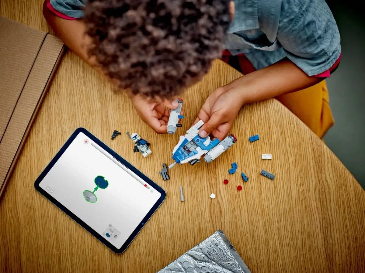 Dziecko układa kreatywne klocki na stole, obok tablet z instrukcją, zabawki edukacyjne  - zabawki-dla-dziewczynki