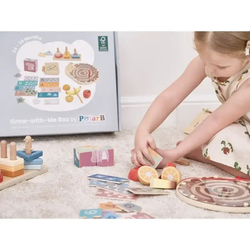 Dziewczynka bawi się drewnianymi, edukacyjnymi zabawkami PolarB na dywanie