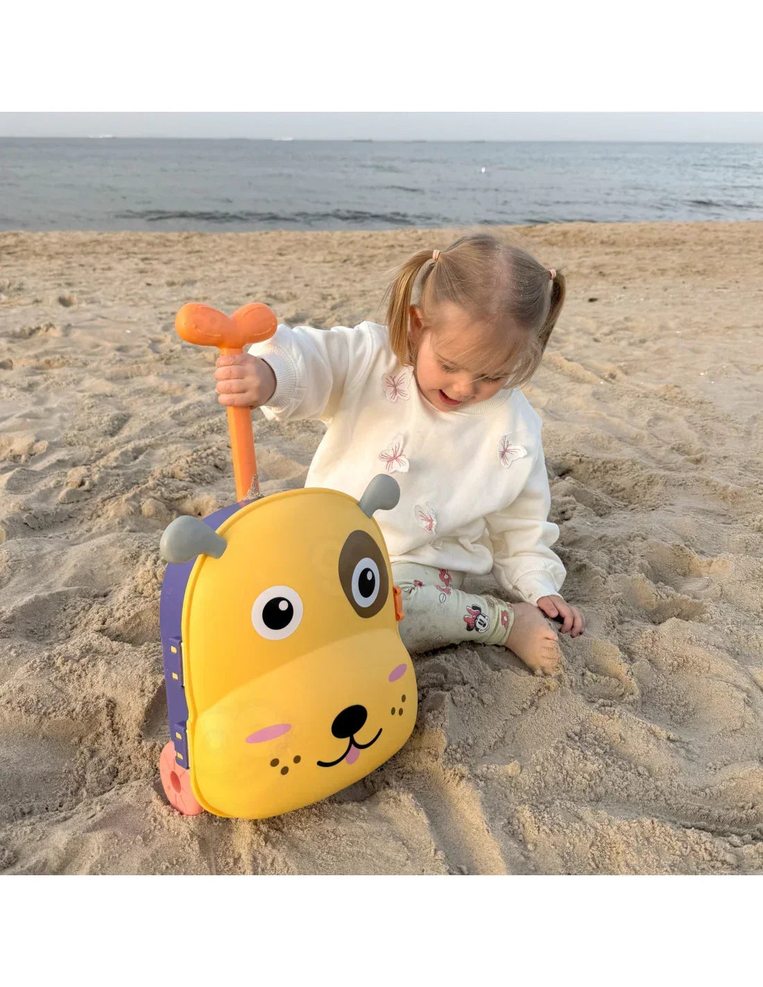 Dziewczynka z żółtą walizką pieskiem bawi się na plaży, zabawki dla dzieci, kreatywna zabawa. zabawki-dla-dziewczynki