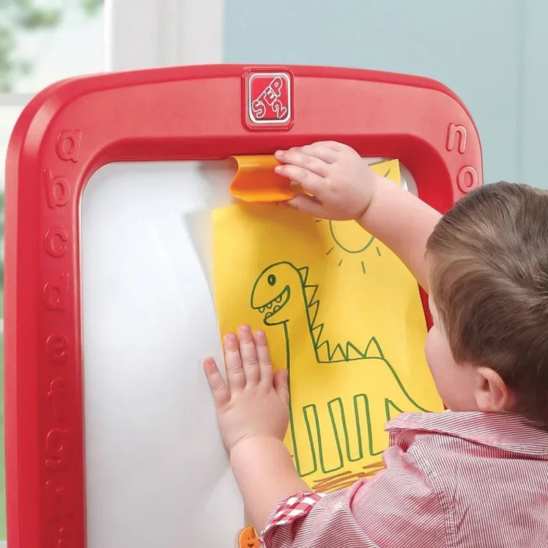 Dziecko rysuje dinozaura na żółtej kartce przy tablicy edukacyjnej Step2, zabawki kreatywne